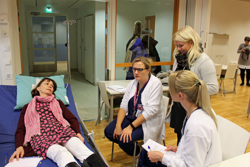 Ruotsinopettaja esittää potilasta, kun sairaanhoitajat harjoittelevat ruotsinkieltä