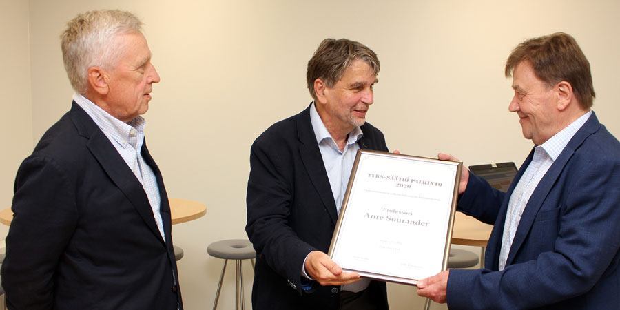Ordföranden Risto Laalo och verksamhetsledaren Olli Ruuskanen överräcker priset till professor André Sourander.