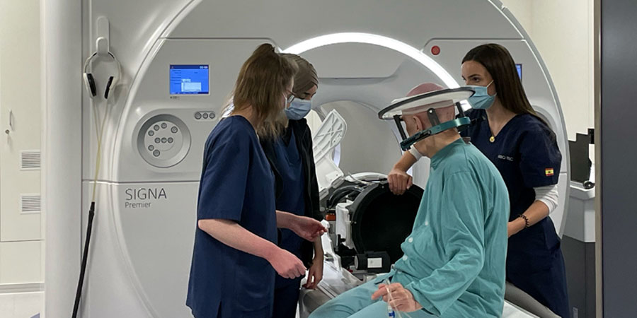 Fyra personer framför en magnetisk resonanstomografi. En av dem har en apparat på huvudet.