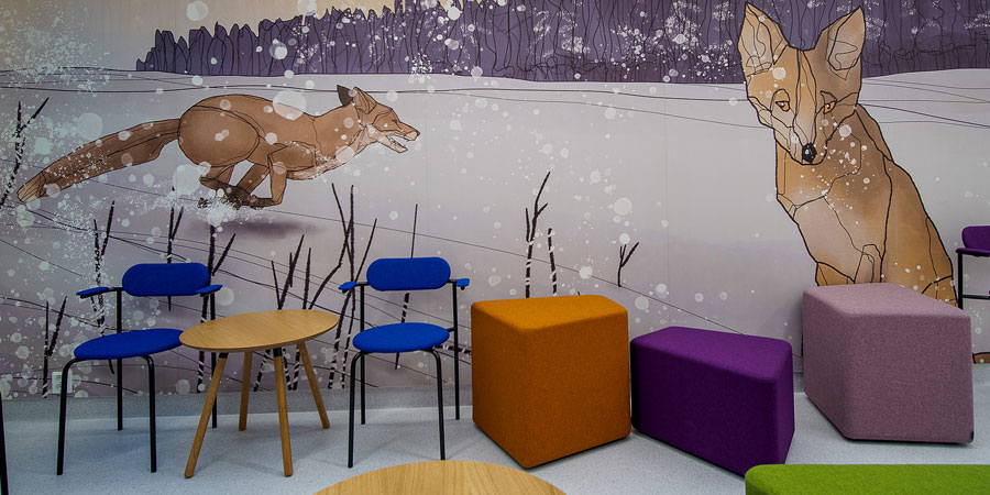 Två rävar på väggen i rummet, färgglada sittplatser framför väggen.
