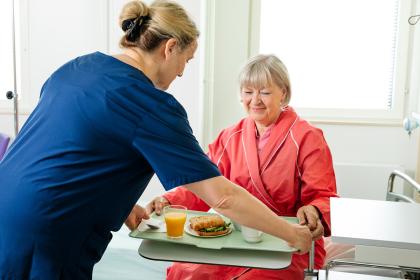 A nurse brings food to the patient on a tray.