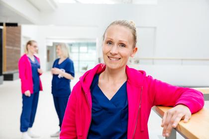 En sjukskötare lutar sig mot räcket och två sjukskötare pratar med varandra i bakgrunden.