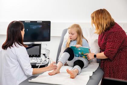 The physician takes an ultrasound image of the child's ankle.
