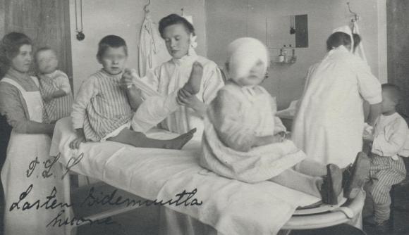 Children and nurses in an early 20th century bandaging room.