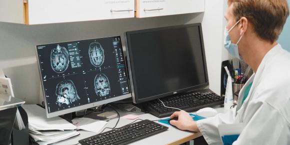 Läkaren undersöker bilder av hjärnan på datorskärmen.