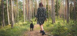 Nainen kävelee metsässä koiran kanssa.